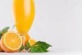 Fresh oranges juice in wineglass with ripe half oranges and green leaf on soft white wood table, copy space, closeup. Royalty Free Stock Photo