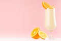 Fresh oranges milkshake with juicy pieces citrus and striped straw in gentle graceful soft pink interior, copy space.