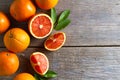 Fresh oranges with slices and leaves on wooden background.