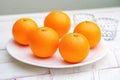 Fresh oranges on white plate with glassware on wooden table Royalty Free Stock Photo
