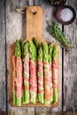 Fresh organic asparagus wrapped in Parma ham on a cutting board Royalty Free Stock Photo