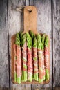 Fresh organic asparagus wrapped in prosciutto on a cutting board Royalty Free Stock Photo