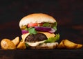 Fresh organic beef burger with cheese  and sauce with vegetables and potato vedges on wooden board. Macro Royalty Free Stock Photo
