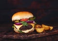 Fresh organic beef burger with cheese  and sauce with vegetables and potato vedges on wooden chopping board Royalty Free Stock Photo