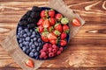 Fresh organic blueberries, blackberries, strawberries, raspberries on a separate dish on a textured wooden background