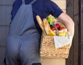 Fresh organic food in a wicker basket in the hands of a bicycle courier. Bike delivery or donation of food concept Royalty Free Stock Photo