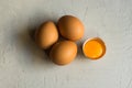 Fresh organic brown eggs, cracked shell, open bright yolk on white concrete table surface, top view, abstract Royalty Free Stock Photo