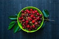 Fresh cherries berries in bright green bowl on dark rustic wooden background Royalty Free Stock Photo