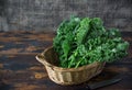 Fresh organic curly kale leaves in a basket with cook knife in a front, on a brown wooden table and on a dark wooden background, Royalty Free Stock Photo