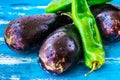 Fresh organic eggplants and green italian pepper with water drops on blue wood background, bright colors, vegetarian clean eating Royalty Free Stock Photo