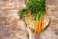 Fresh organic farmer carrots bunch with green tops in a basket on wooden rustic kitchen table, top down view Royalty Free Stock Photo