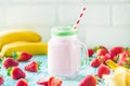 Fresh organic farmers strawberry and banana milk shake pouring from the bottle in a jar glass