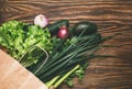 Fresh organic food in crafting paper bag, fresh vegetables. Salad, cucumber, celery, onion, avocado and parsley on wooden