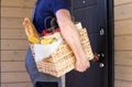 Fresh organic food in a wicker basket in the hands of a bicycle courier. Bike delivery or donation of food concept Royalty Free Stock Photo