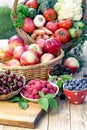 Fresh organic fruits and vegetables in bowls and baskets on wooden table closeup Royalty Free Stock Photo