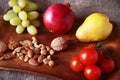 Fresh organic fruits and vegetables on wooden Serving tray. Assorted apple, pear, grapes, tomatoes and nuts. Royalty Free Stock Photo