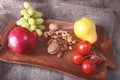 Fresh organic fruits and vegetables on wooden Serving tray. Assorted apple, pear, grapes, tomatoes and nuts. Royalty Free Stock Photo