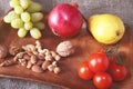 Fresh organic fruits and vegetables on wooden Serving tray. Assorted apple, pear, grapes, tomatoes and nuts. Royalty Free Stock Photo