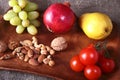 Fresh organic fruits and vegetables on wooden Serving tray. Assorted apple, pear, grapes, tomatoes and nuts. Royalty Free Stock Photo