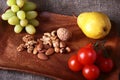 Fresh organic fruits and vegetables on wooden Serving tray. Assorted apple, pear, grapes, tomatoes and nuts. Royalty Free Stock Photo