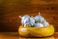 Garlic in a hand turned wooden bowl on a reclaimed hard wood background.