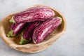 Fresh organic Graffiti eggplants in a wooden bowl on a concrete background. Royalty Free Stock Photo