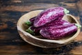 Fresh organic Graffiti eggplants in a wooden bowl on an old wooden table. Royalty Free Stock Photo