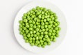 Fresh organic green peas on a round white plate isolated on white, top view, with space for text Royalty Free Stock Photo