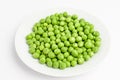 Fresh organic green peas on a white plate isolated on white, side view of healthy raw vegan food, with space for text Royalty Free Stock Photo