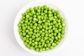 Fresh organic green peas in a white round bowl on a table in soft focus, isolated on white, top view Royalty Free Stock Photo