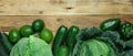 Fresh organic green vegetables savoy cabbage zucchini cucumbers bell peppers avocados on rustic plank wood background. Superfoods