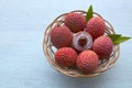 Fresh organic lychees in a basket on a light blue wooden background.Exotic tropical lichi fruits.Raw diet or vegan food concept.