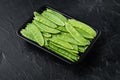 Fresh organic mangetout, also known as sugar snap pea, in plastic container, on black stone background , with copyspace and space