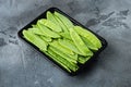 Fresh organic mangetout, also known as sugar snap pea, in plastic container, on gray stone background