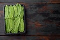 Fresh organic mangetout, also known as sugar snap pea, in plastic container, on old dark wooden table background, top view flat