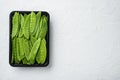 Fresh organic mangetout, also known as sugar snap pea, in plastic container, on white stone background, top view flat lay , with