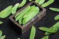 Fresh organic mangetout, also known as sugar snap pea, in wooden box, on black stone background