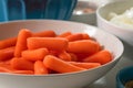 Fresh organic peeled baby carrots close up on a plate among other vegetables on a kitchen table