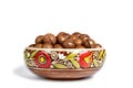 Fresh organic peeled macadamia nuts in ceramic bowl isolated on white