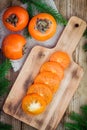 Fresh organic persimmon with slices on wooden board Royalty Free Stock Photo