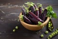 Fresh organic purple green peas in a wooden bowl on rustic wooden table. Royalty Free Stock Photo