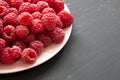 Fresh organic raspberry on a pink plate on black surface, low angle view. Close-up Royalty Free Stock Photo