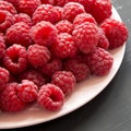 Fresh organic raspberry on a pink plate on black surface, low angle view. Close-up. Copy space Royalty Free Stock Photo