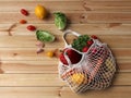 Fresh organic raw carrots, lettuce, paprika, lemons, radishes in a white net bag on a light wooden background Royalty Free Stock Photo