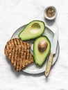 Fresh organic ripe avocado and whole grain grilled bread - delicious healthy breakfast, snack on light background, top view