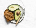 Fresh organic ripe avocado and whole grain grilled toast bread - delicious healthy breakfast, snack on light background, top view