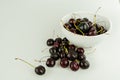 Fresh organic ripe black cherries in a bowl and spread around on an isolated white background Royalty Free Stock Photo