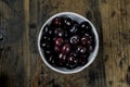 Fresh organic ripe black cherries in a white bowl on a rustic wooden table Royalty Free Stock Photo