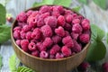 Fresh organic ripe raspberry with leaf in bowl on wooden table