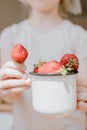 Fresh organic Strawberries in children hands. Girl child holding fresh red organic strawberries in white enameled cup. Summer